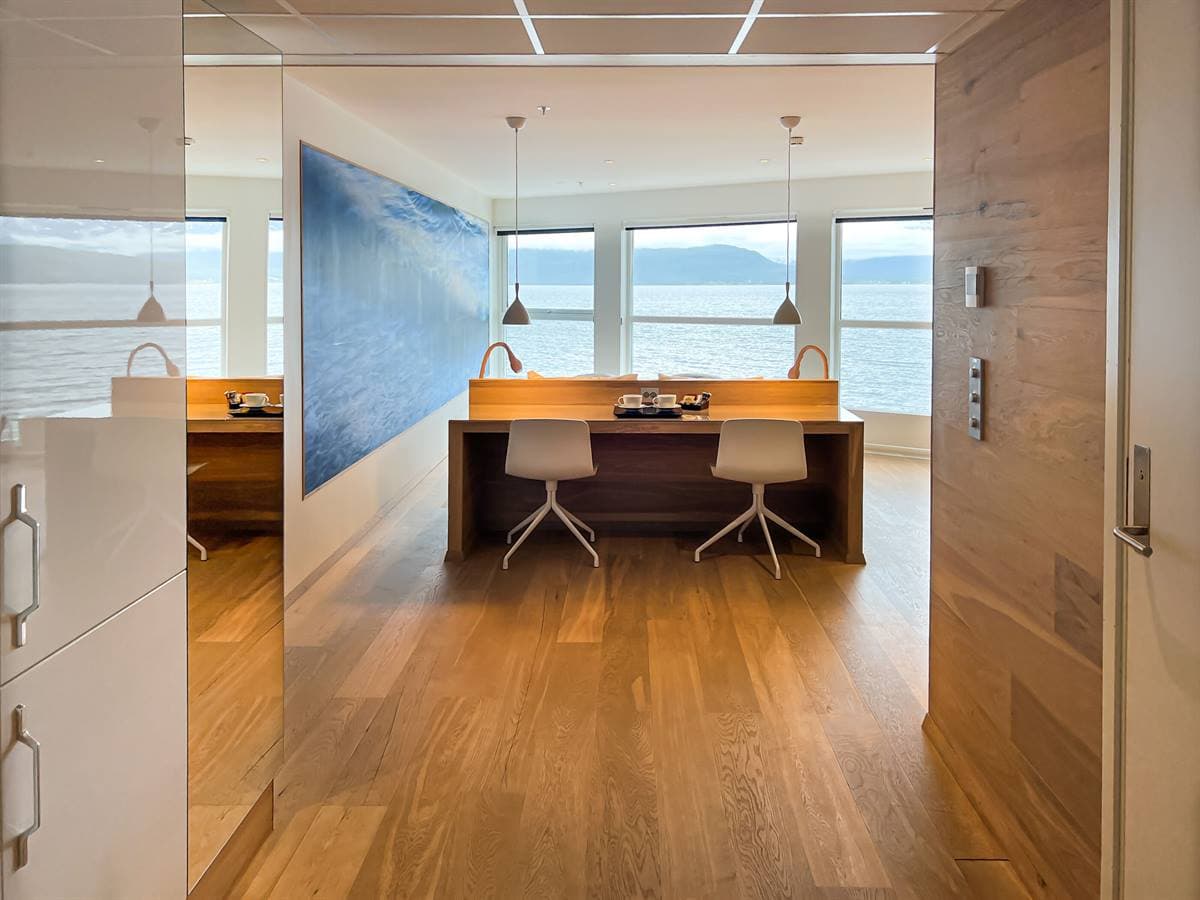 Work desk behind a glass partition in the Junior Suite, with a wave mural and fjord windows