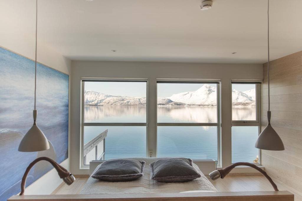 Premium Double Room with the bed facing windows over the winter fjord and snow-capped mountains