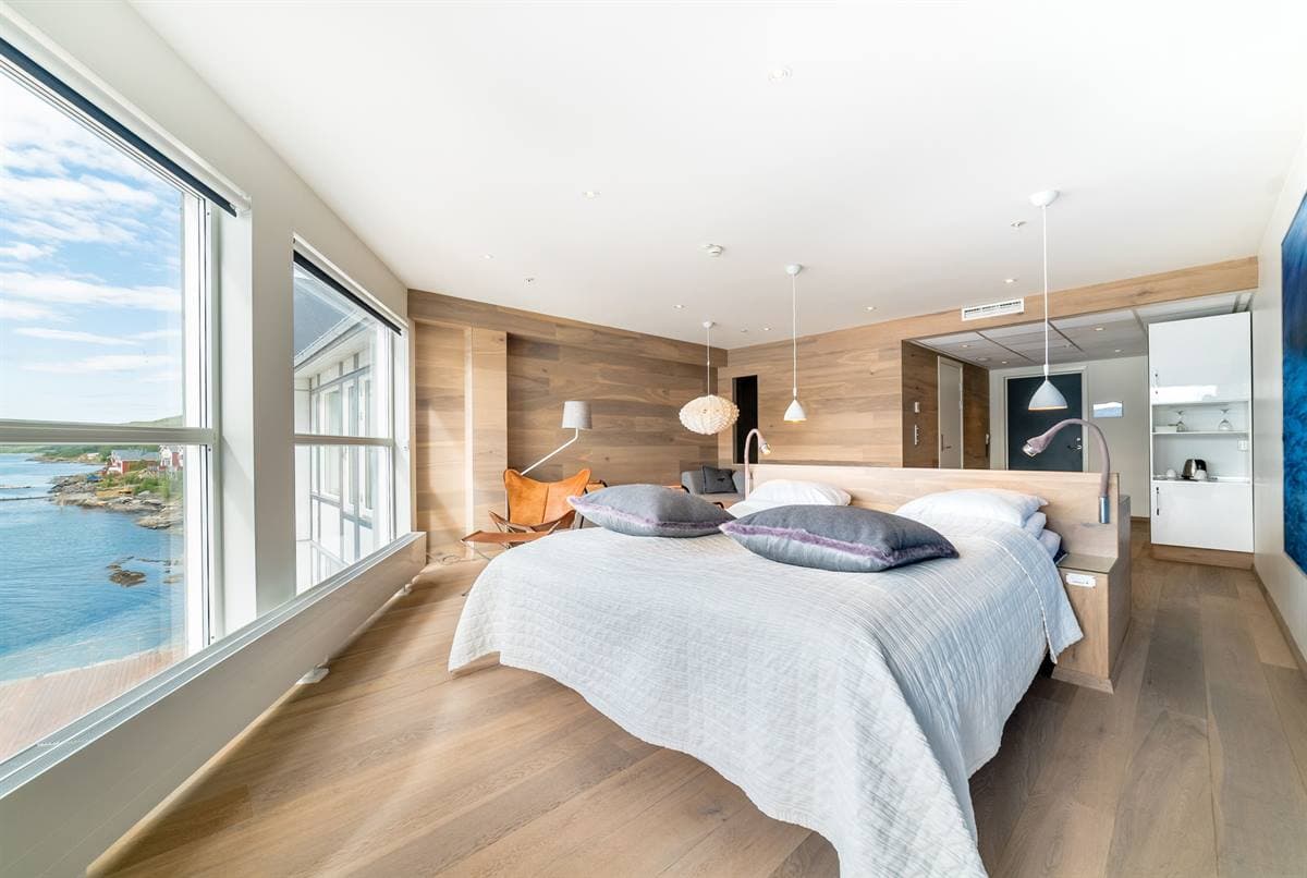 Junior Suite with double bed, seating and large windows towards the fjord