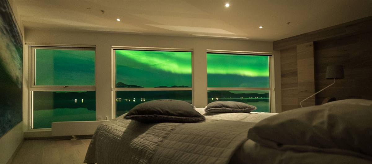 Hotel room at night with the northern lights outside three large windows