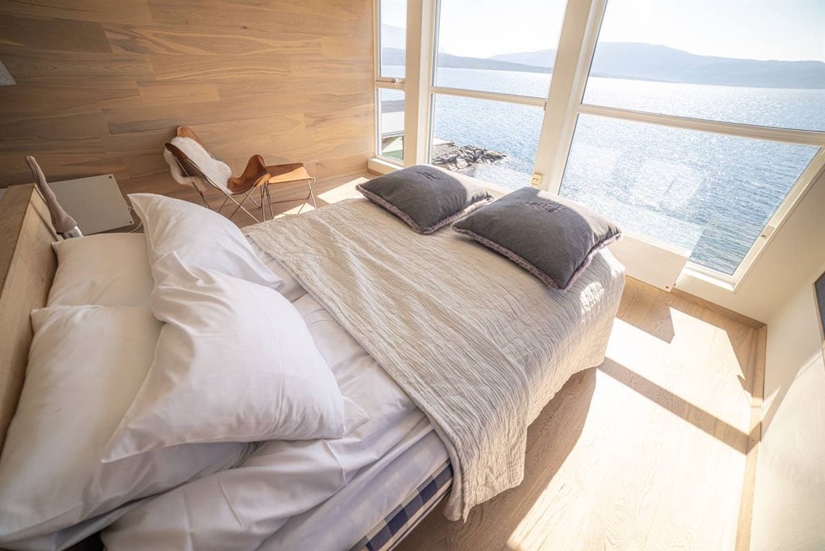 Bed under large angled windows facing the fjord in a Premium Double Room