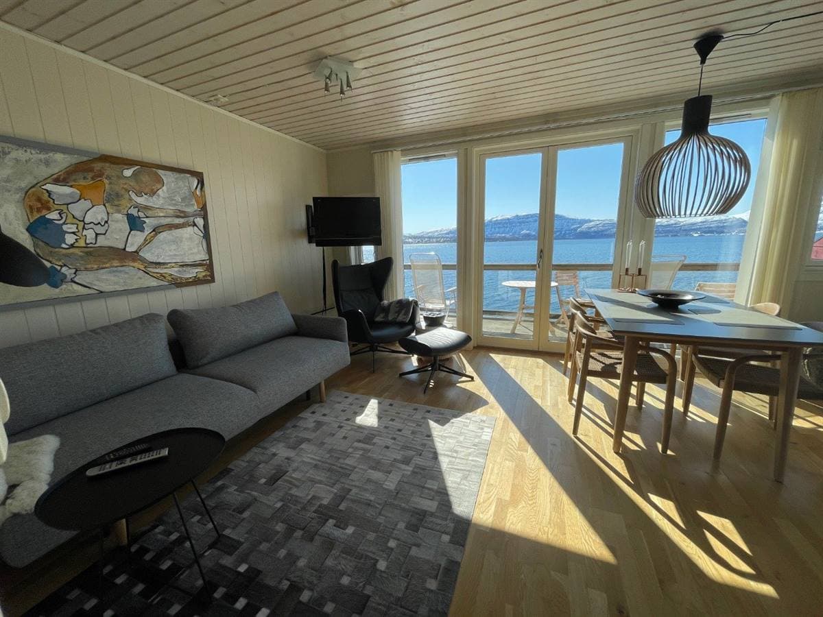 Apartment living and dining area with a fjord view through the balcony doors