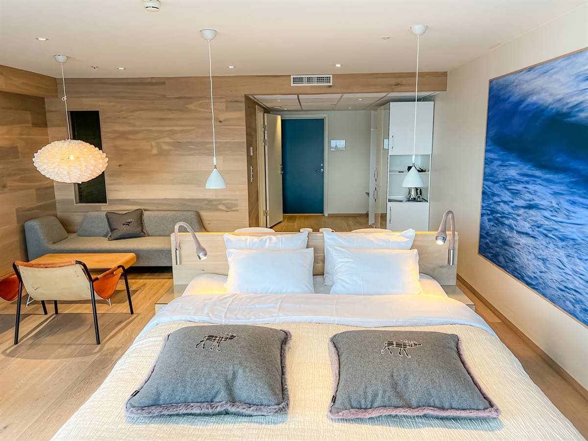 Double bed, sofa corner and a large seascape print in the Junior Suite