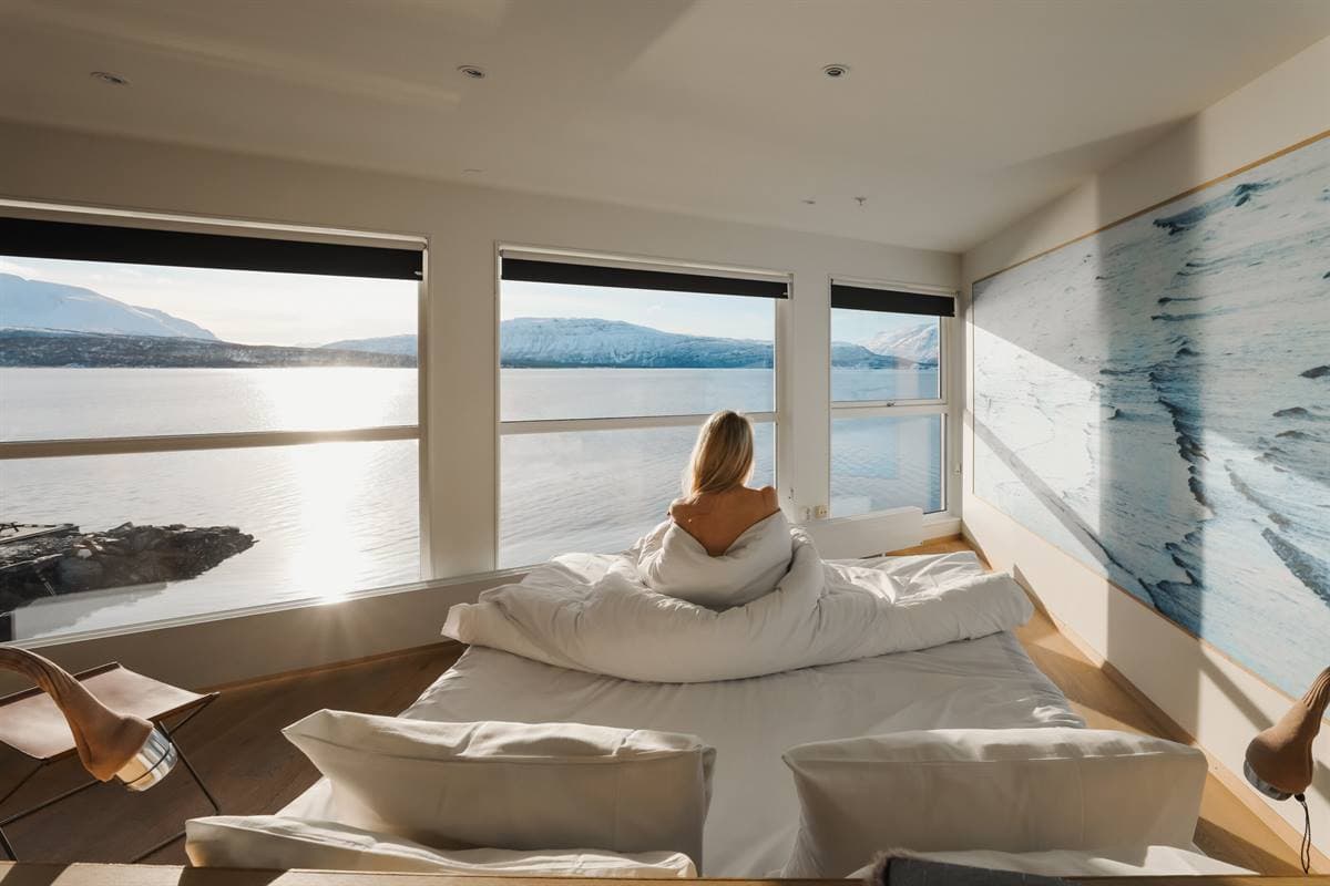 Guest in bed looking out at the fjord
